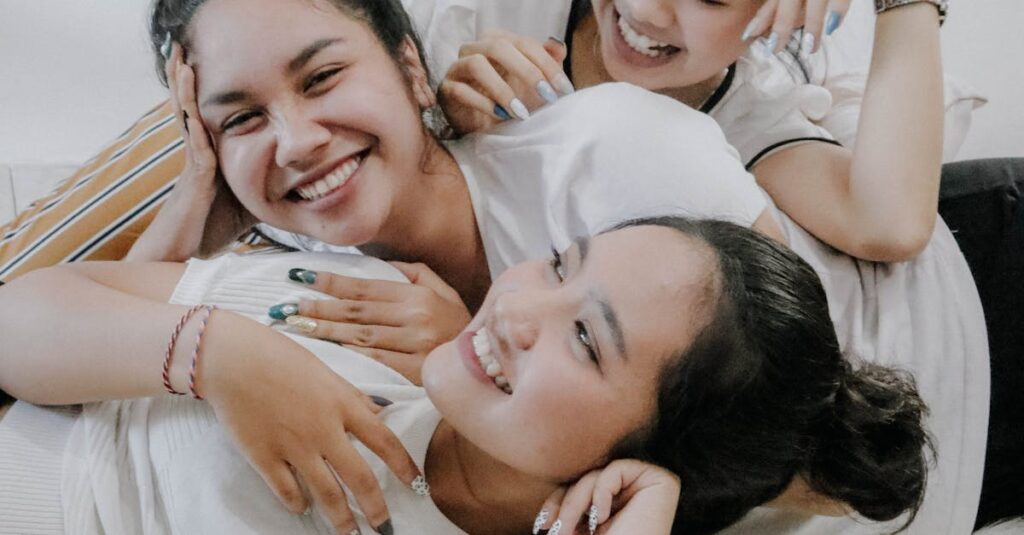 Three young women laughing and embracing each other indoors, showcasing friendship and happiness.
