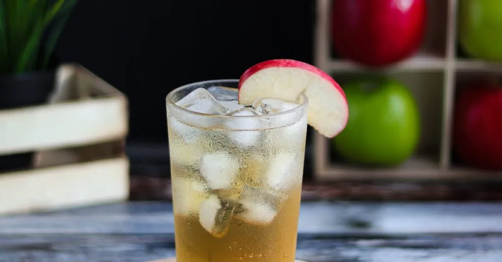 Kidney Stones: How to out Without Surgery or Pain Chilled glass of apple juice with ice cubes and fresh apples on a rustic wooden table.