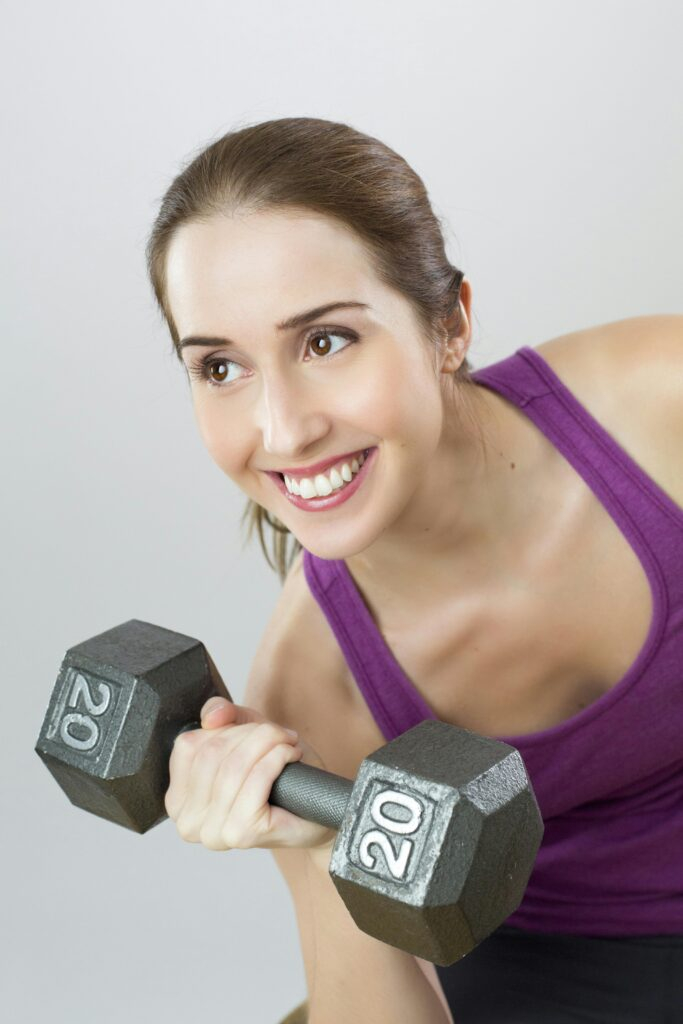 exercise-weight-woman-sport-34669 Young woman exercises with 20 lb dumbbell, showing strength and positivity.